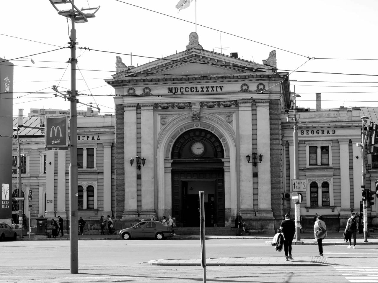 capital crowd building serbia railway station arch urban street — free black and white photo