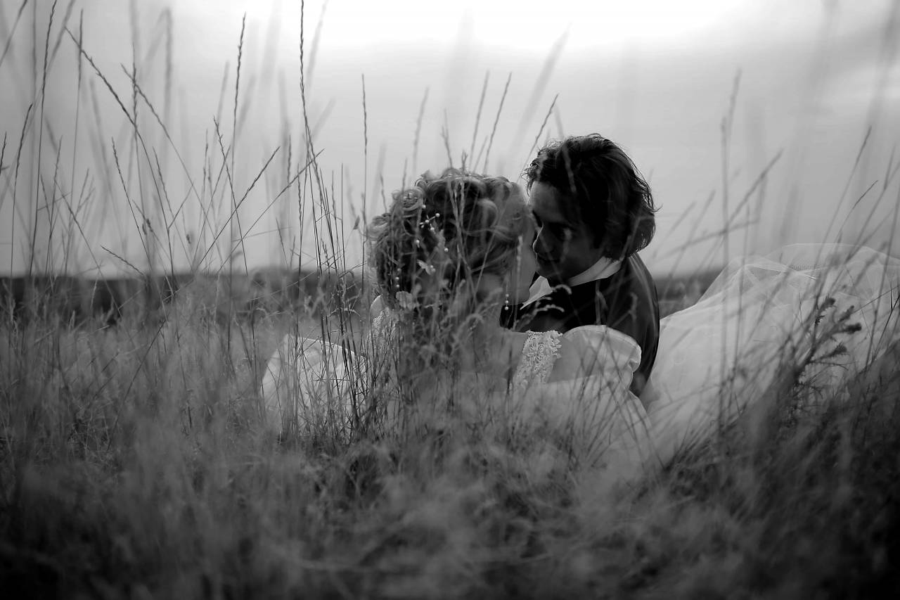 grass laying wife field married husband hugging kiss vrouw vaststelling knuffelen tot kus  korenveld romantische liefde mensen — free black and white photo