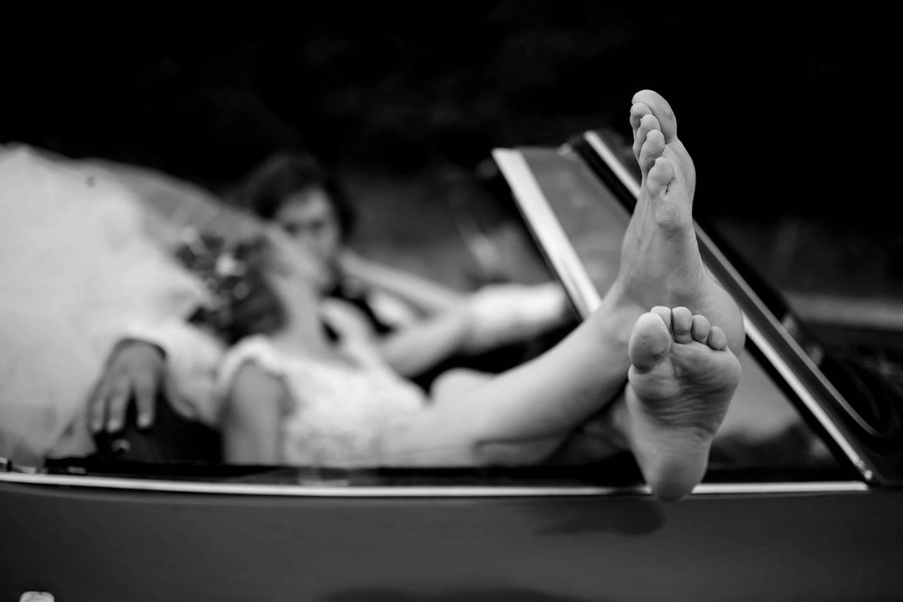 kiss legs barefoot married bride woman groom convertible outdoors — free black and white photo