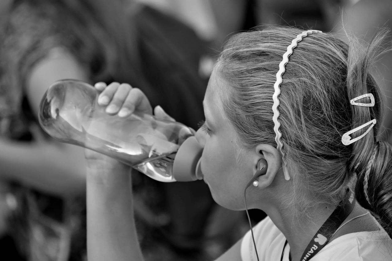 drinking water child bottled crowd fun summer earphones children tourist hairstyle happy beach boy  person — free black and white photo