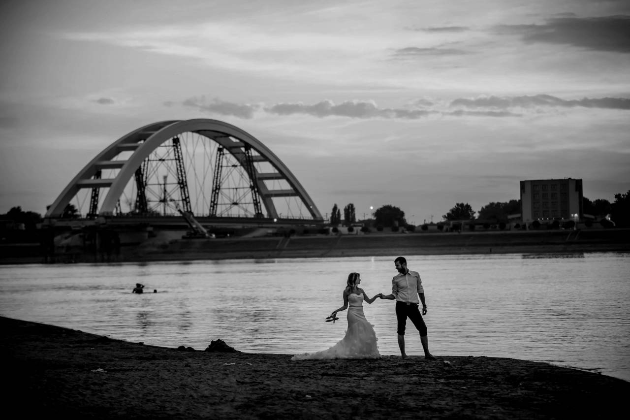 evening sunset romantic bridge beach sea newlyweds water dawn groom  exhilaration jumping happiness bride — free black and white photo