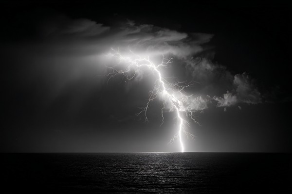 fine art photograph of a lightning bolt striking over a dark — black and white photo