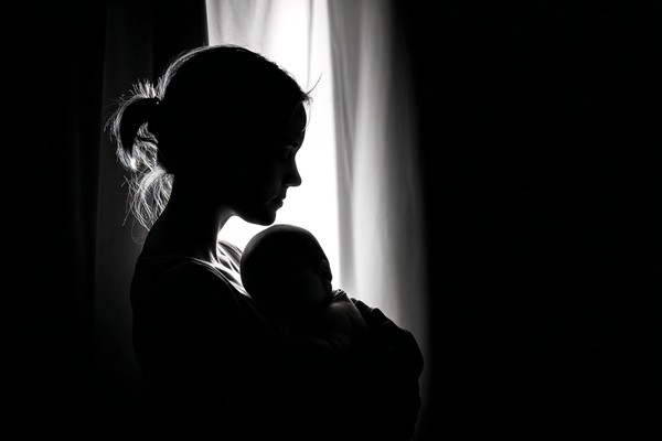 infant black and white picture mother holding baby near windo — black and white photo