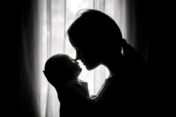 infant black and white picture mother holding baby near windo — black and white photo