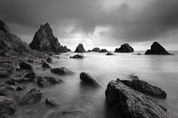 long exposure seascape silky smooth water moving around jagge — black and white photo