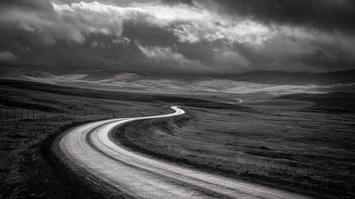 a winding road through a desolate landscape leading line comp — free black and white photo