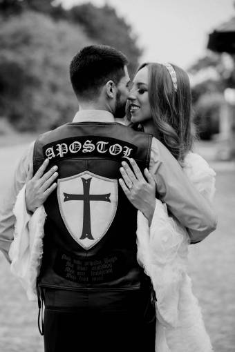 motorcyclist hugging groom bride kiss woman wedding man  — black and white photo
